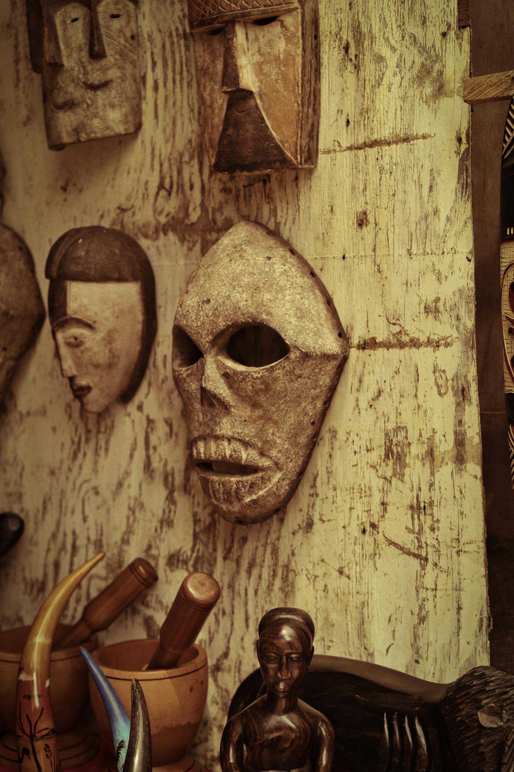 Rustic display of traditional African masks and sculptures in warm tones.
